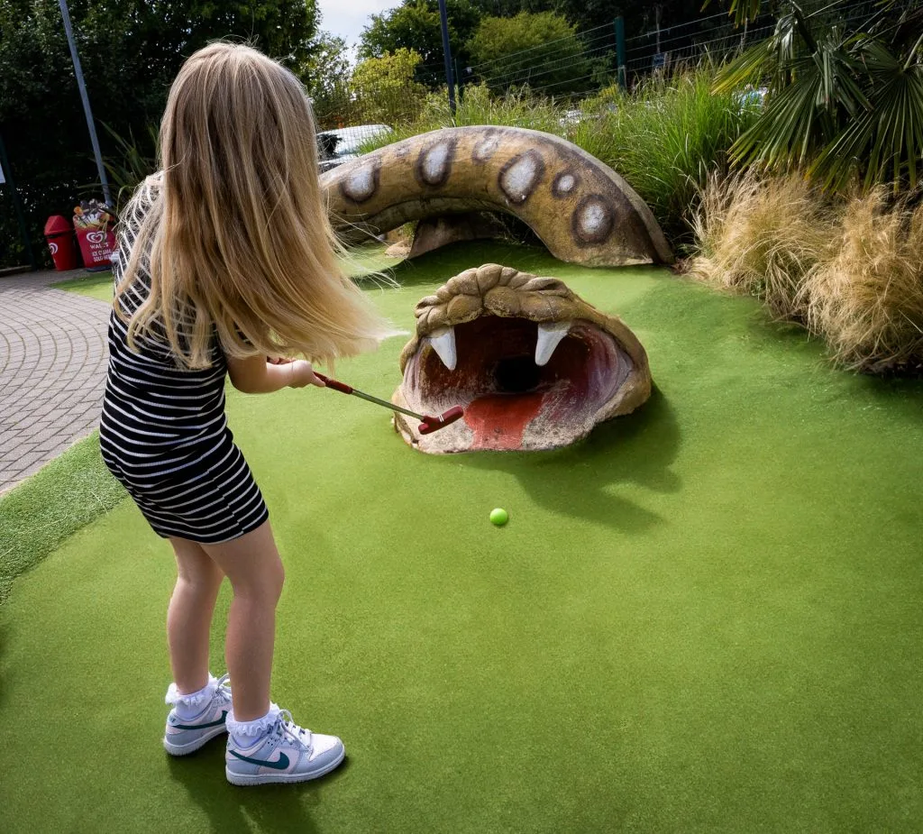 young girl playing mini golf in nottingham hitting a ball into a snakes mouth